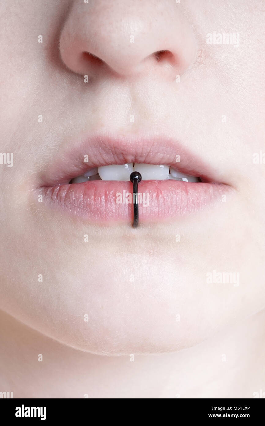 close-up of pierced female lips with vertical labret piercing or lip ring Stock Photo