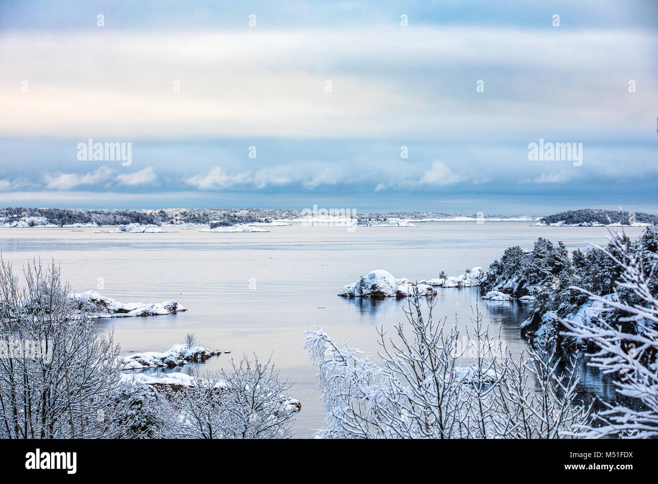 Beautiful winter day at Odderoya in Kristiansand, Norway. Trees covered in snow. The ocean and archipelago in the background. Stock Photo