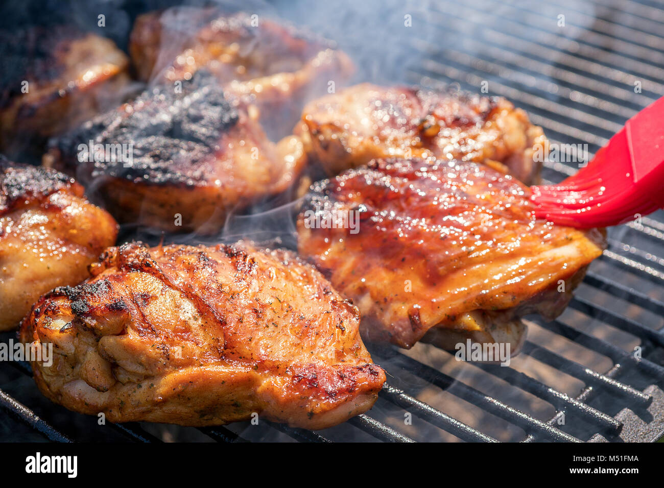 Grilled chicken thigh on the flaming grill Stock Photo