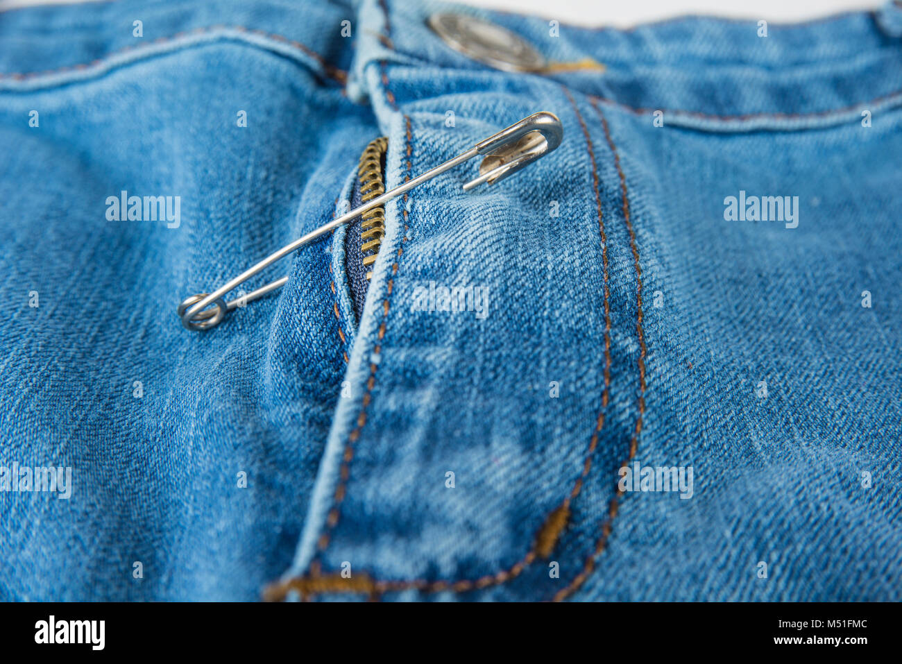 Broken blue jeans zipper fixed with safety pin Stock Photo Alamy