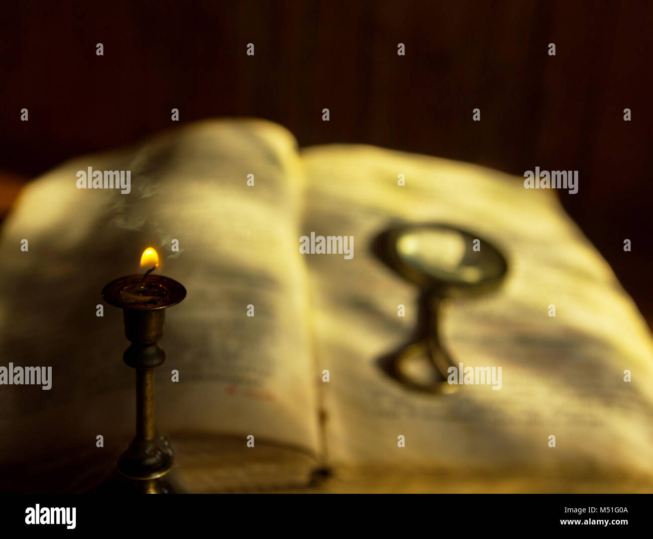 a dying candle and an old book with a magnifying glass Stock Photo Alamy