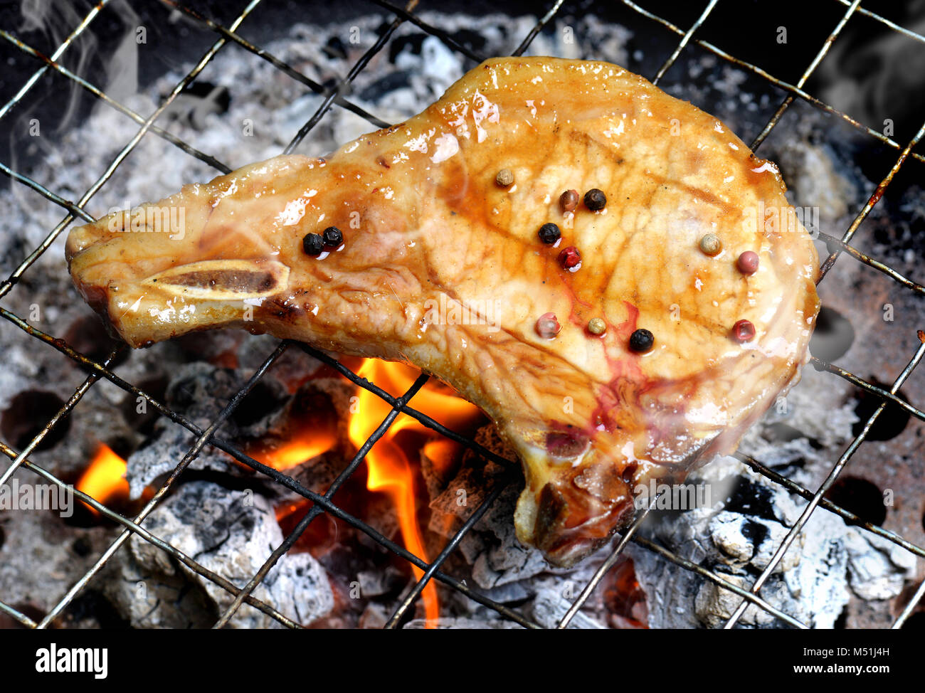 Pork chops steak grill on charcoal fire add on BBQ sauce with outdoor lighting and flash lighting. Stock Photo