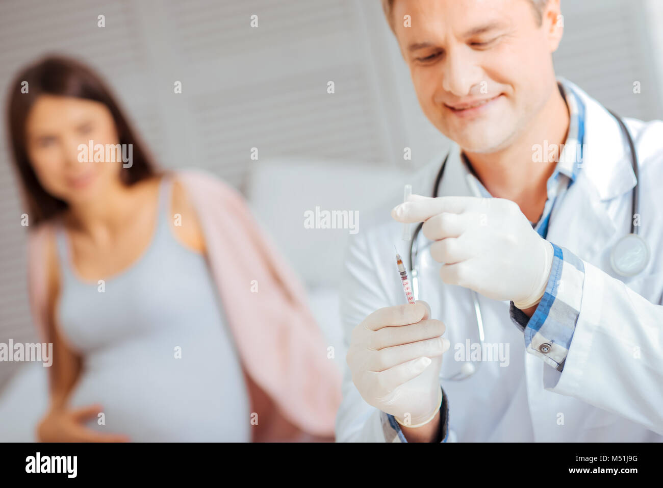 Doctor preparing syringe before injecting pregnant woman Stock Photo