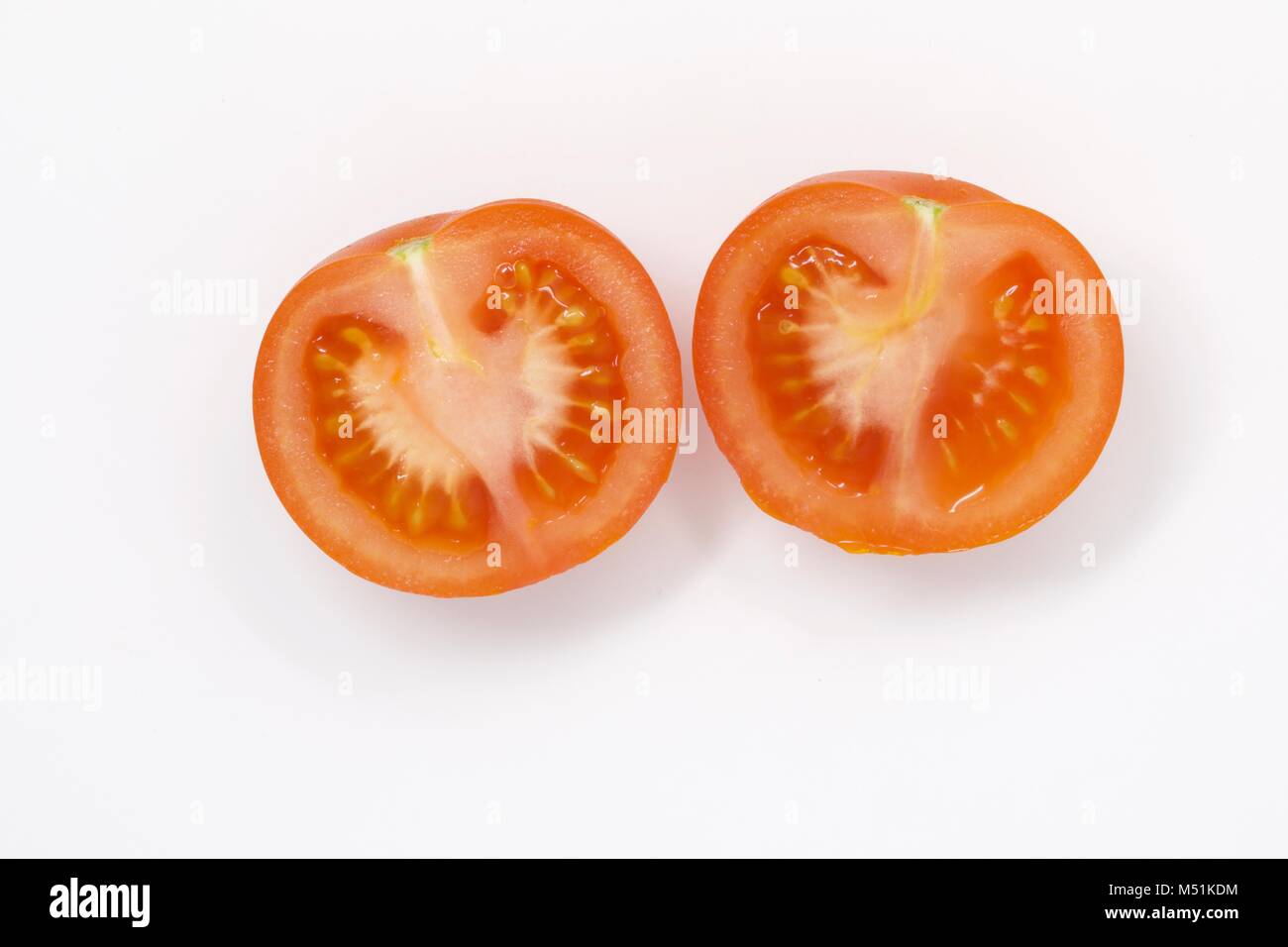 A tomato sliced in half on a white plain background Stock Photo