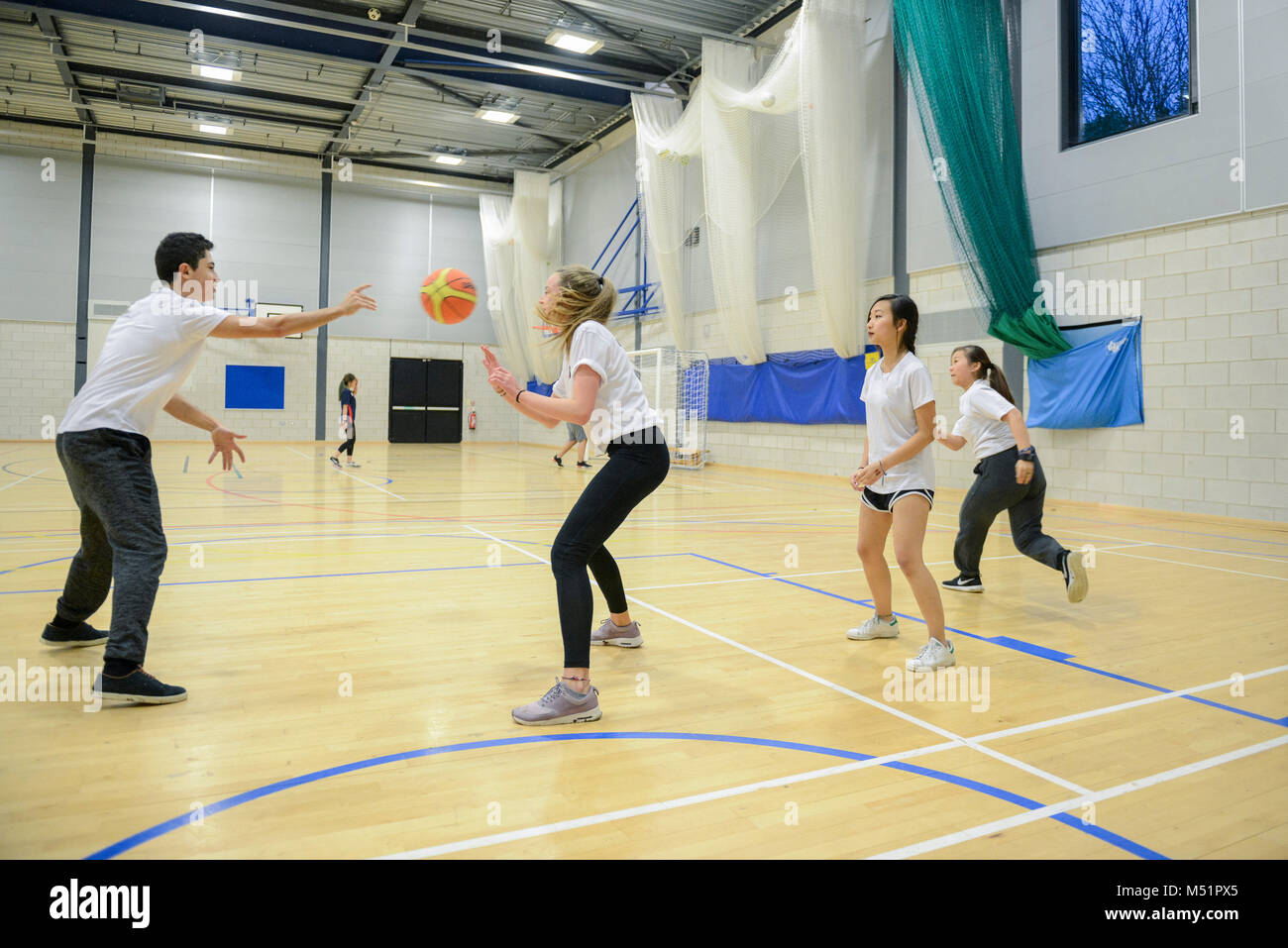 school students playing sports in the indoor sports hall at their
