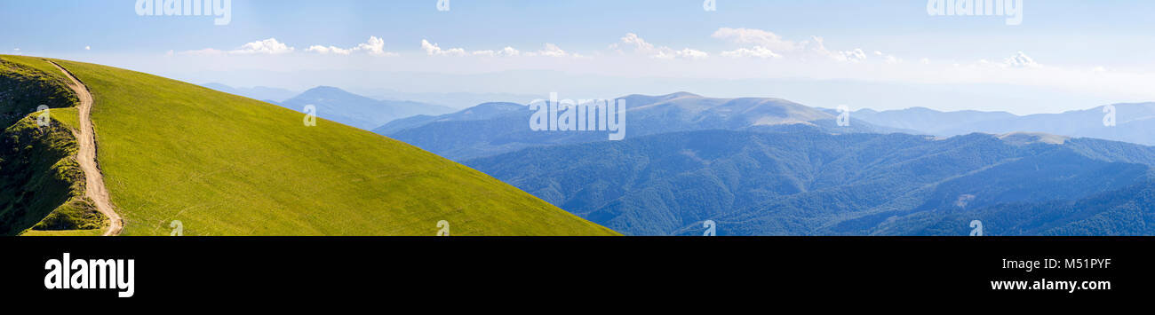 Panorama of green hills in summer mountains with gravel road for ...