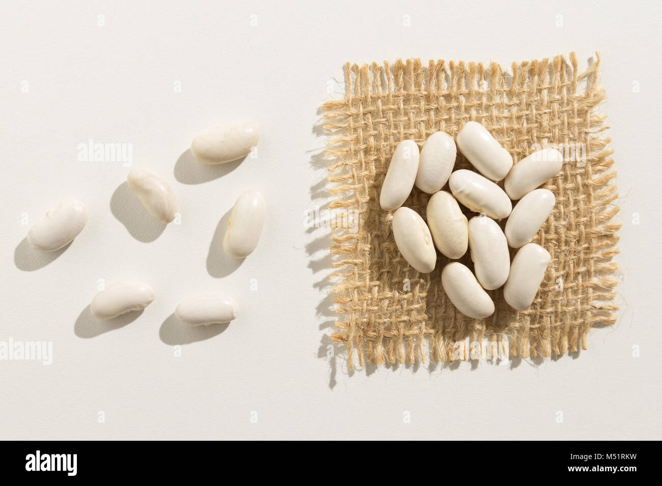 Phaseolus vulgaris is scientific name of Navy Bean legume. Also known as Haricot, Pearl Bean and Feijao Branco. Close up of grains spreaded over white Stock Photo