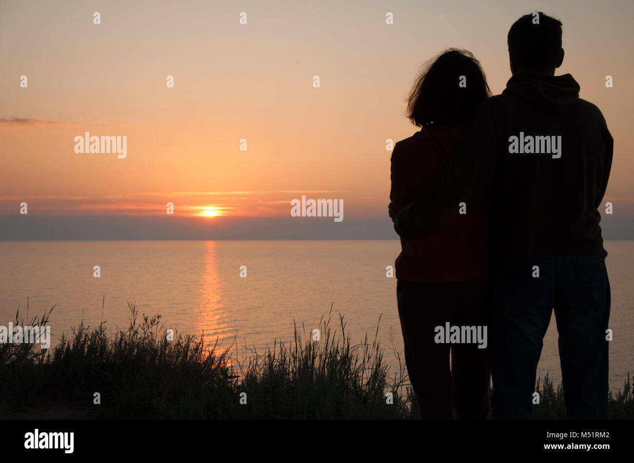 Dawn on the sea. Romantic couple meets the sun rising above the sea surface. Stock Photo