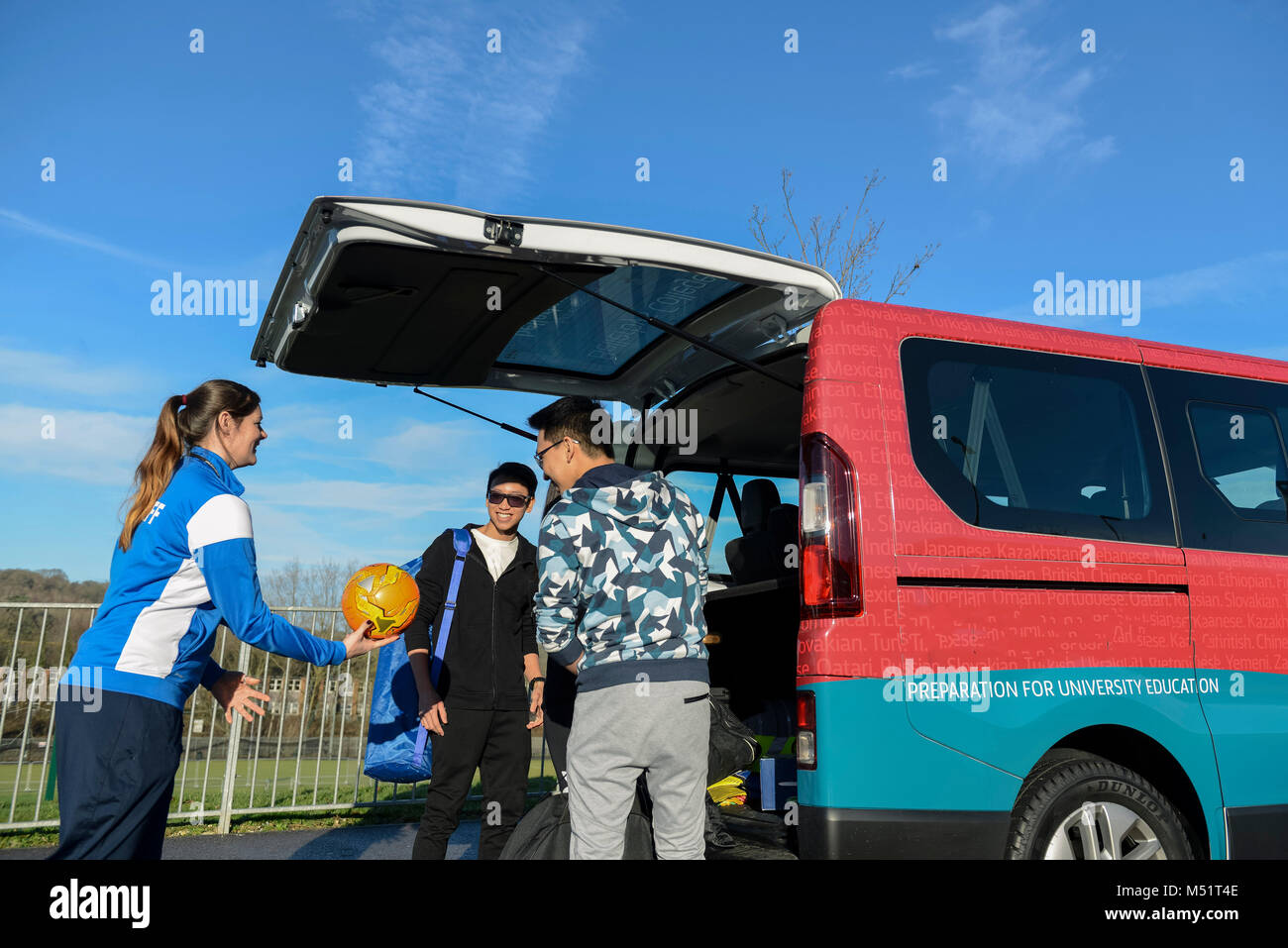 school college kids taking physical education / p.e. sports equipment out of the school van / mini bus before having a games / fitness lesson Stock Photo