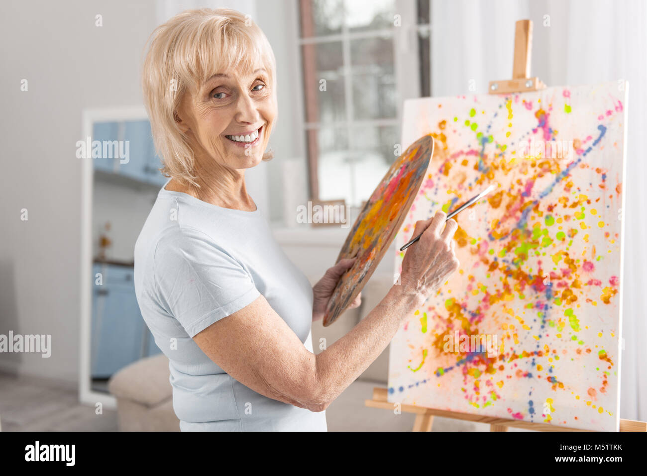 Happy mature woman finishing painting Stock Photo