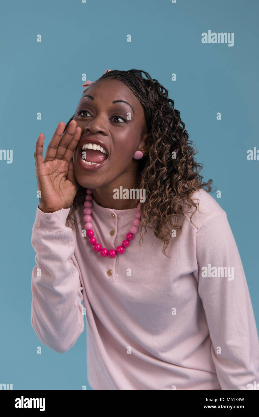 Young African Woman Shout And Scream Using Her Hands As Tube Studio Shoot Isolated On Blue Young African Woman Shout And Scream Using Her Hands As Tube Studio Shoot Isolated On Blue
