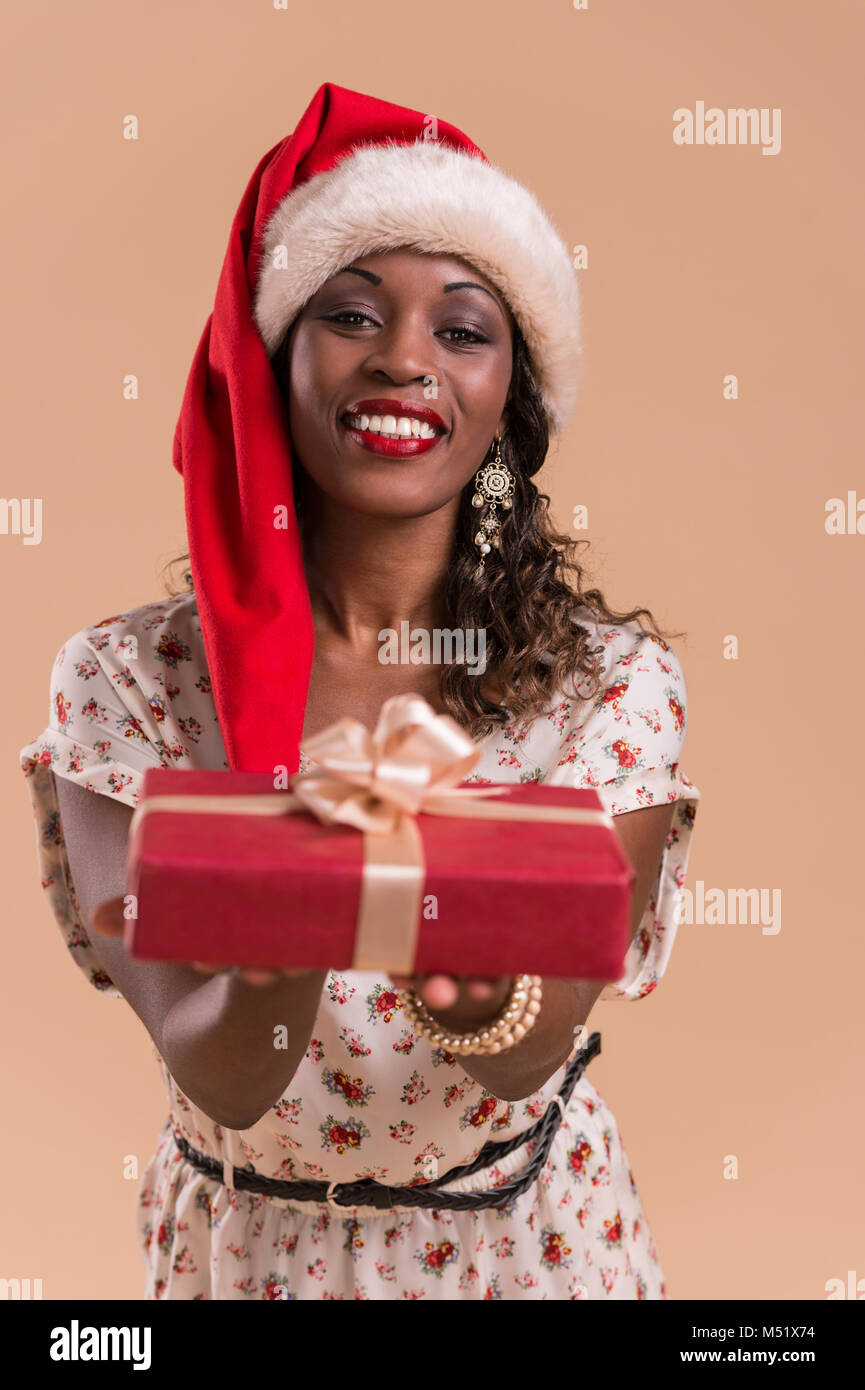 African Christmas woman wearing Santa Claus hat holding gift Stock Photo