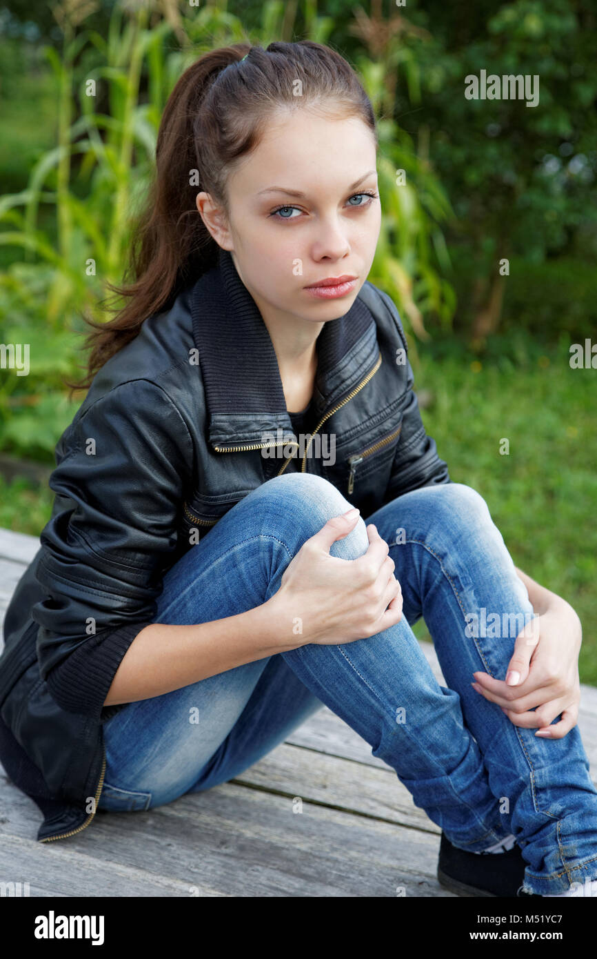The girl sitting on wooden boards in a summer garden Stock Photo - Alamy