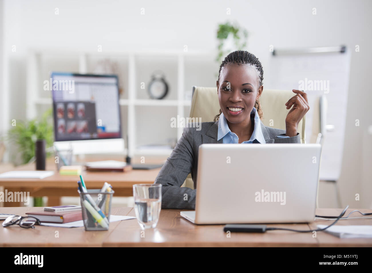 Pretty cheerful african businesswoman working with laptop in office and ...