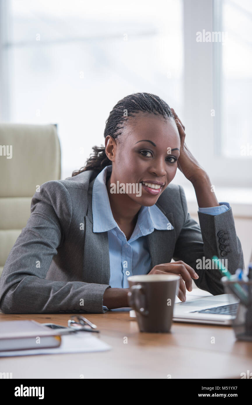 Pretty cheerful african businesswoman working with laptop in office and ...