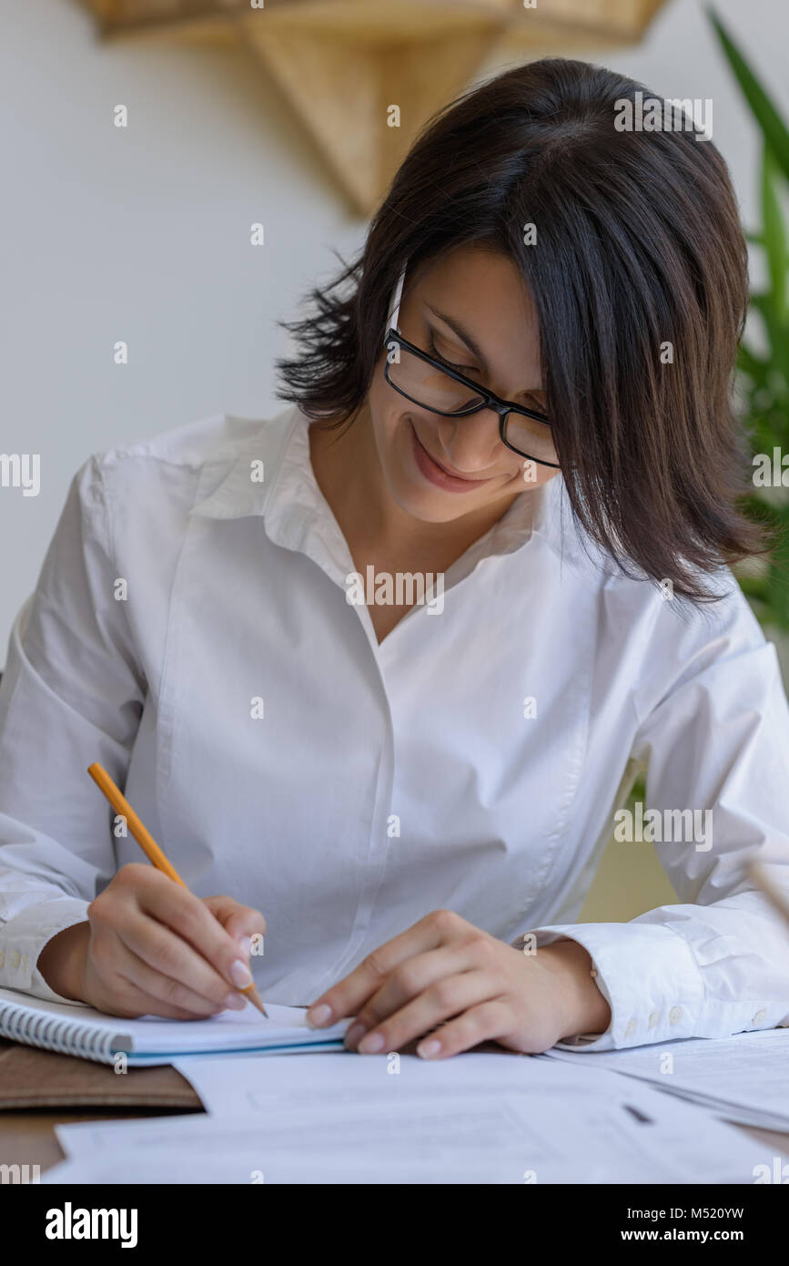 Woman writing at office during working day Stock Photo - Alamy