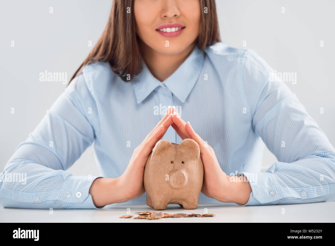 Happy business woman covering piggy bank with two hands - safety for ...