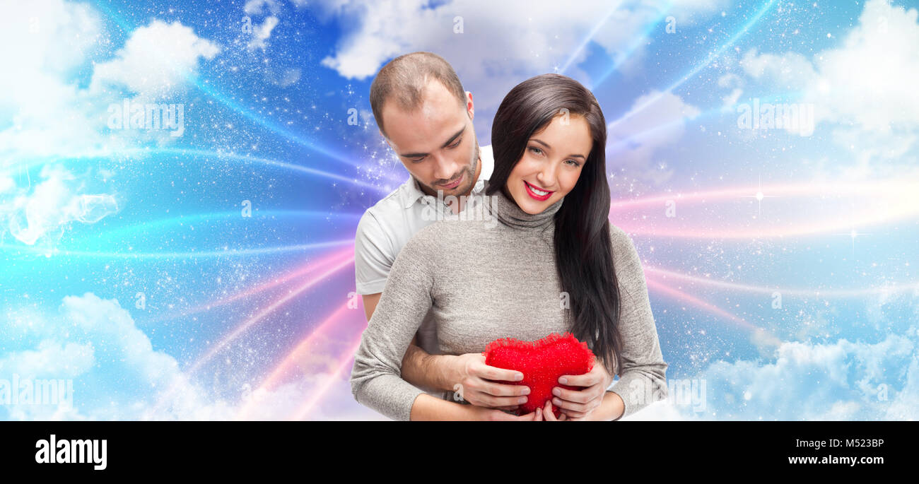Happy young adult couple with red heart on romantic background with sky ...