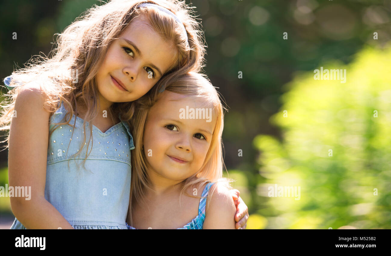 Outdoor portrait of two embracing cute little girls Stock Photo - Alamy