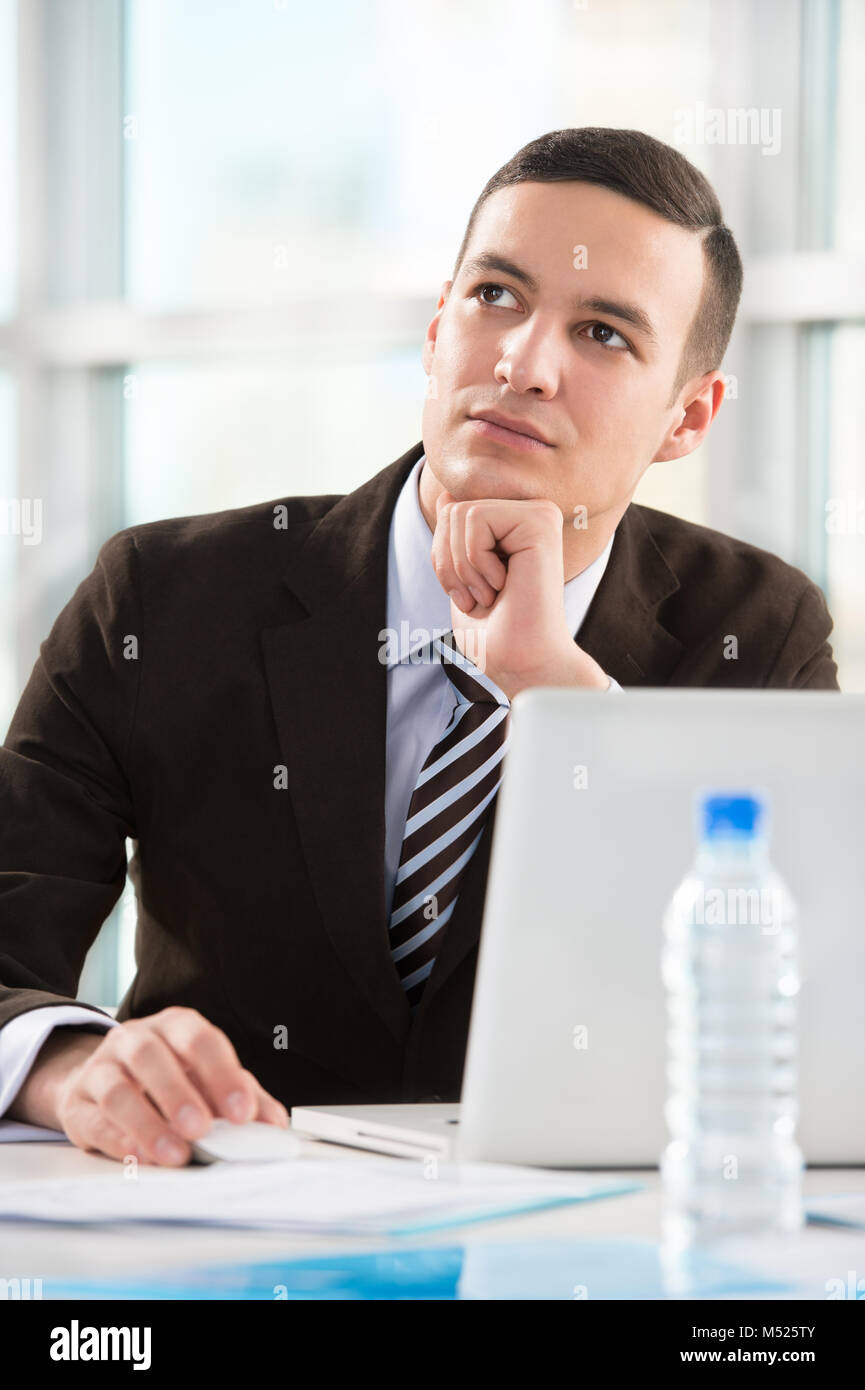 Business man at his office working with laptop and thinking about his ...