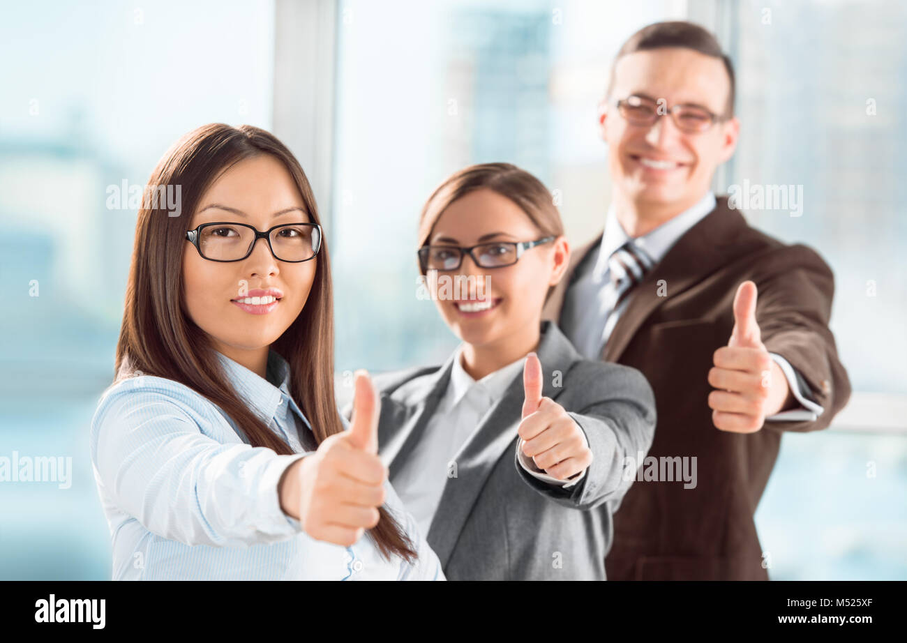 Successful young business people showing thumbs up sign Stock Photo - Alamy