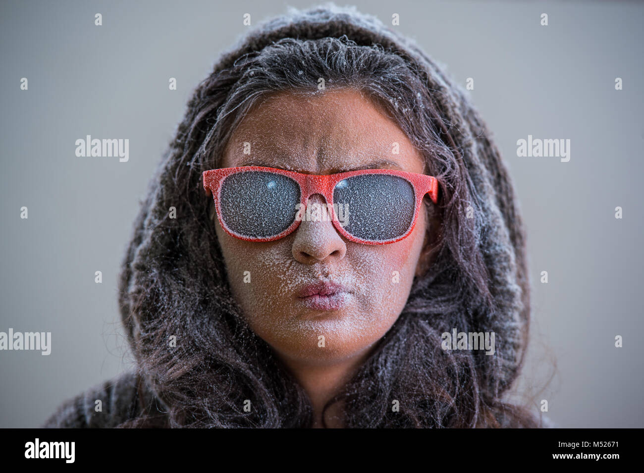 Pretty woman wearing winter outfit and sunglasses. Bemused expression on her face Stock Photo