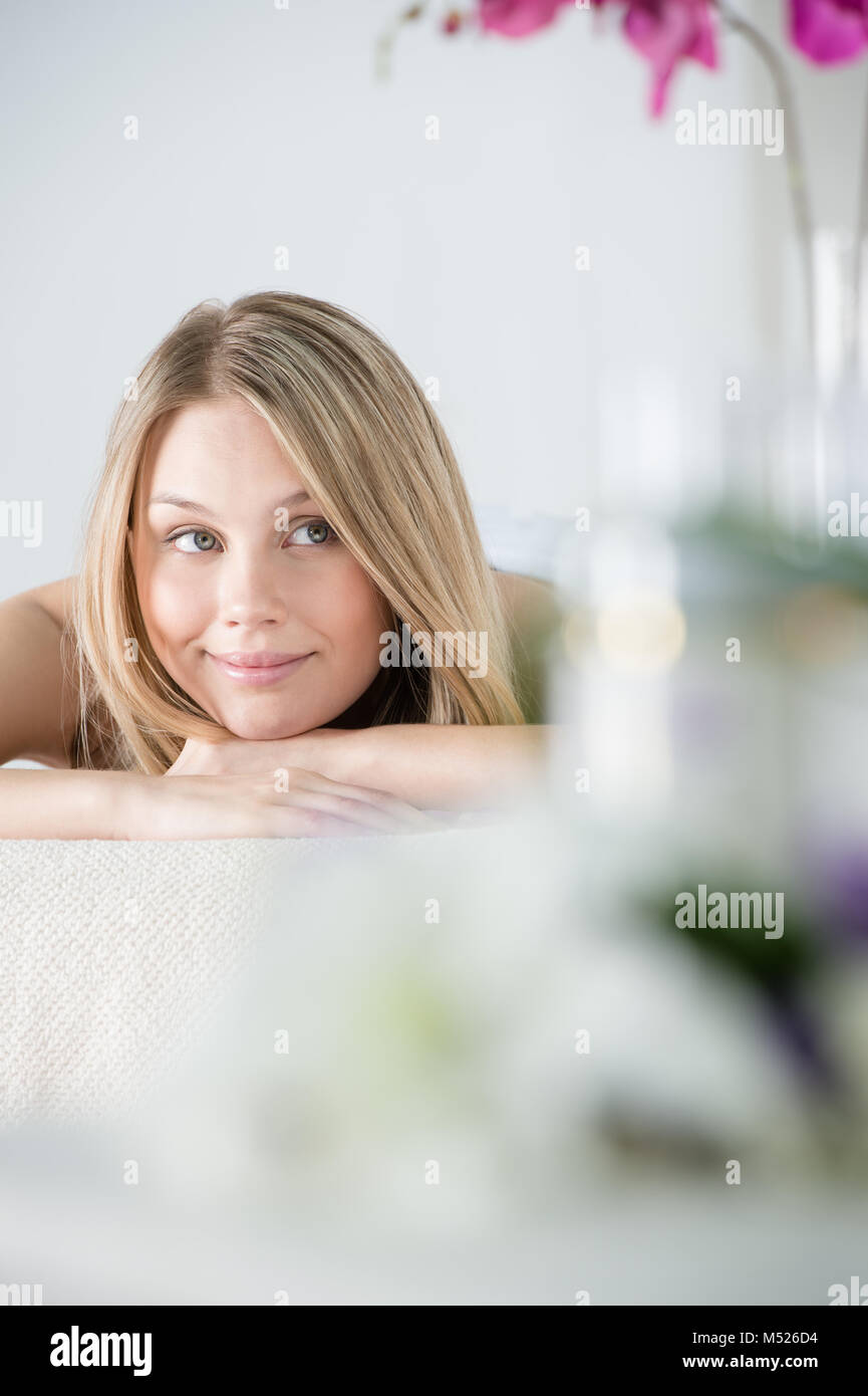 Woman on spa or massage with flowers and cosmetics on foreground making perfect copyspace Stock Photo