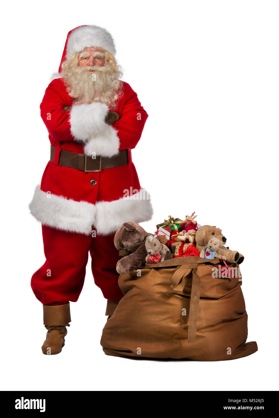 Full length portrait of a Santa Claus posing near a bag full of gifts ...