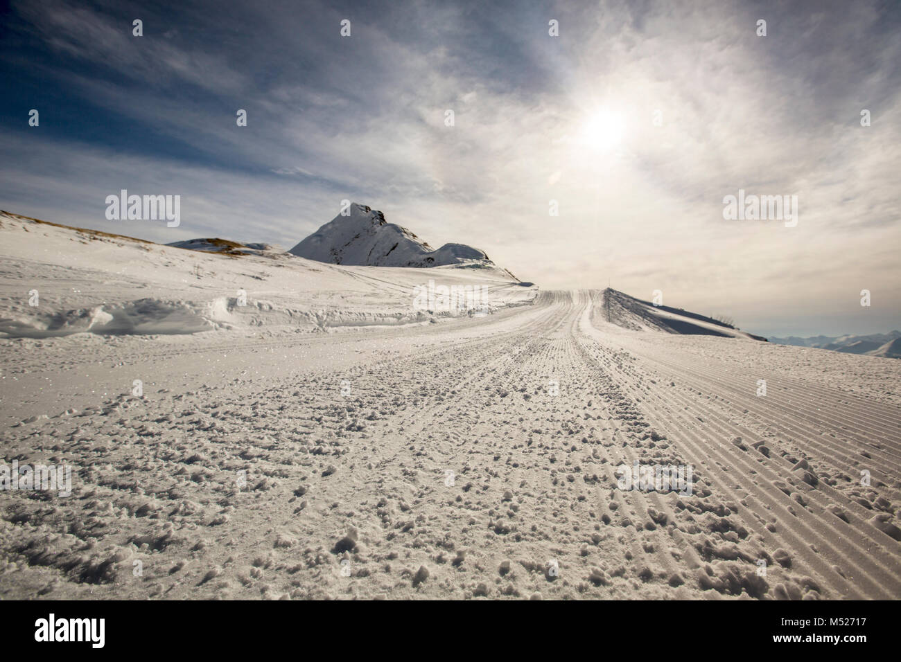 Ski track in snow as abstract background, bright winter sun on clear blue sky Stock Photo