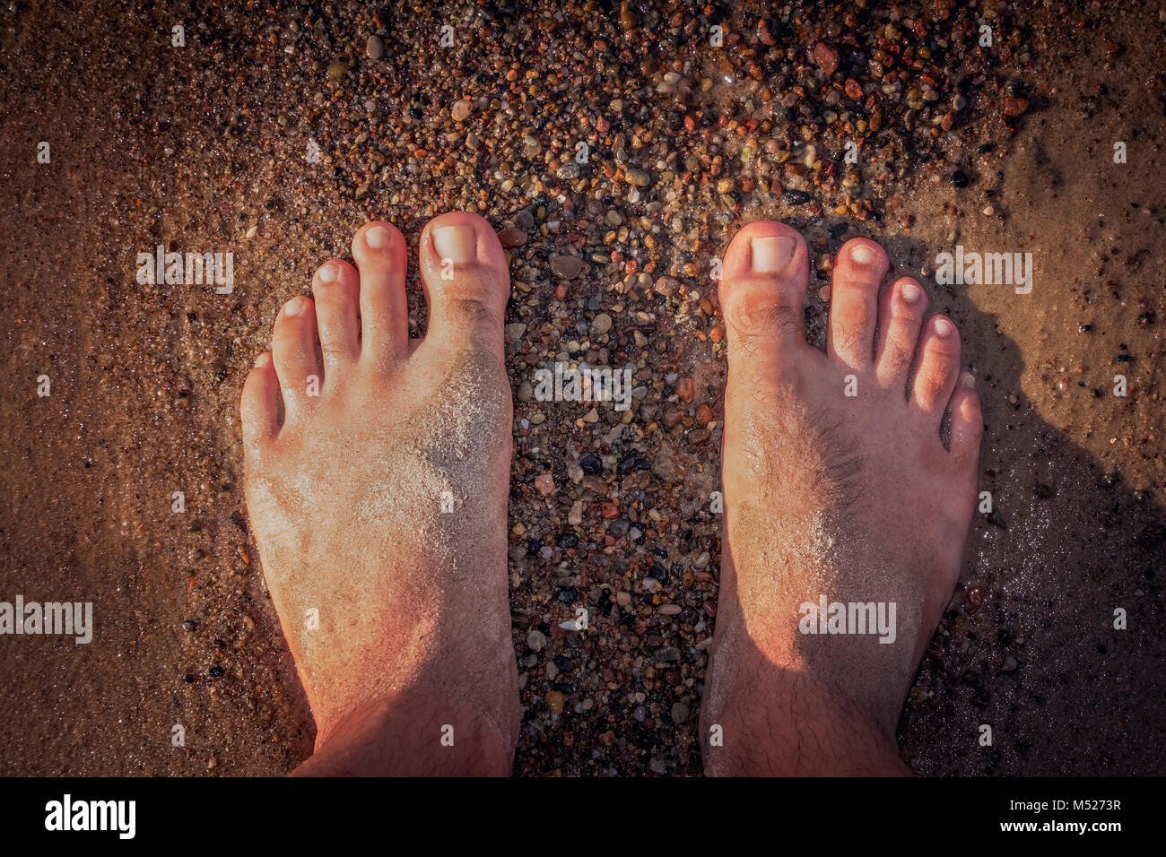 Mans feet on the seashore Stock Photo