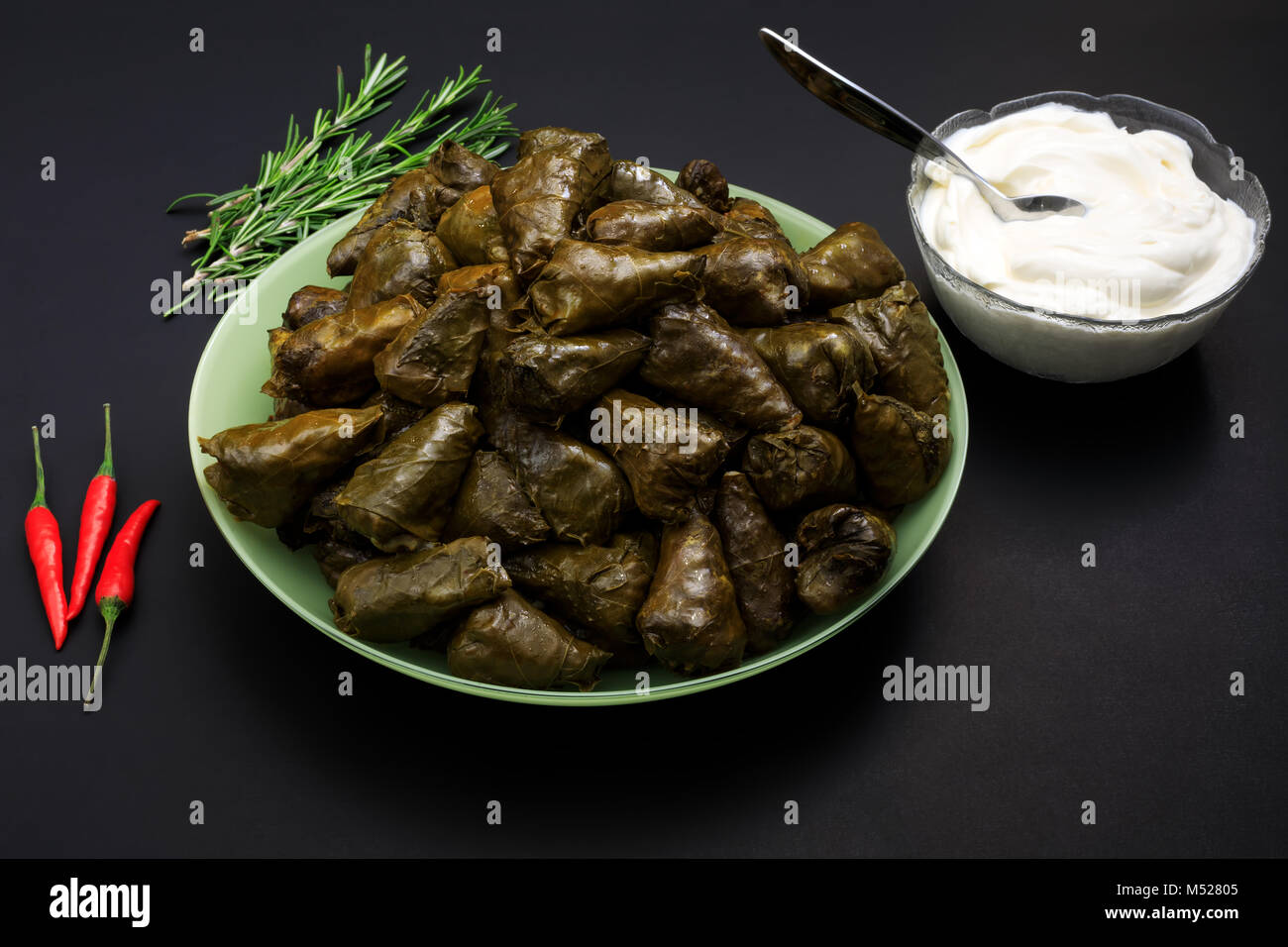 Sarmale, dolma, sarma, golubtsy or golabki. Grape vines leaves stuffed with meat, rice and vegetables with sour cream. European traditional cuisine. Stock Photo
