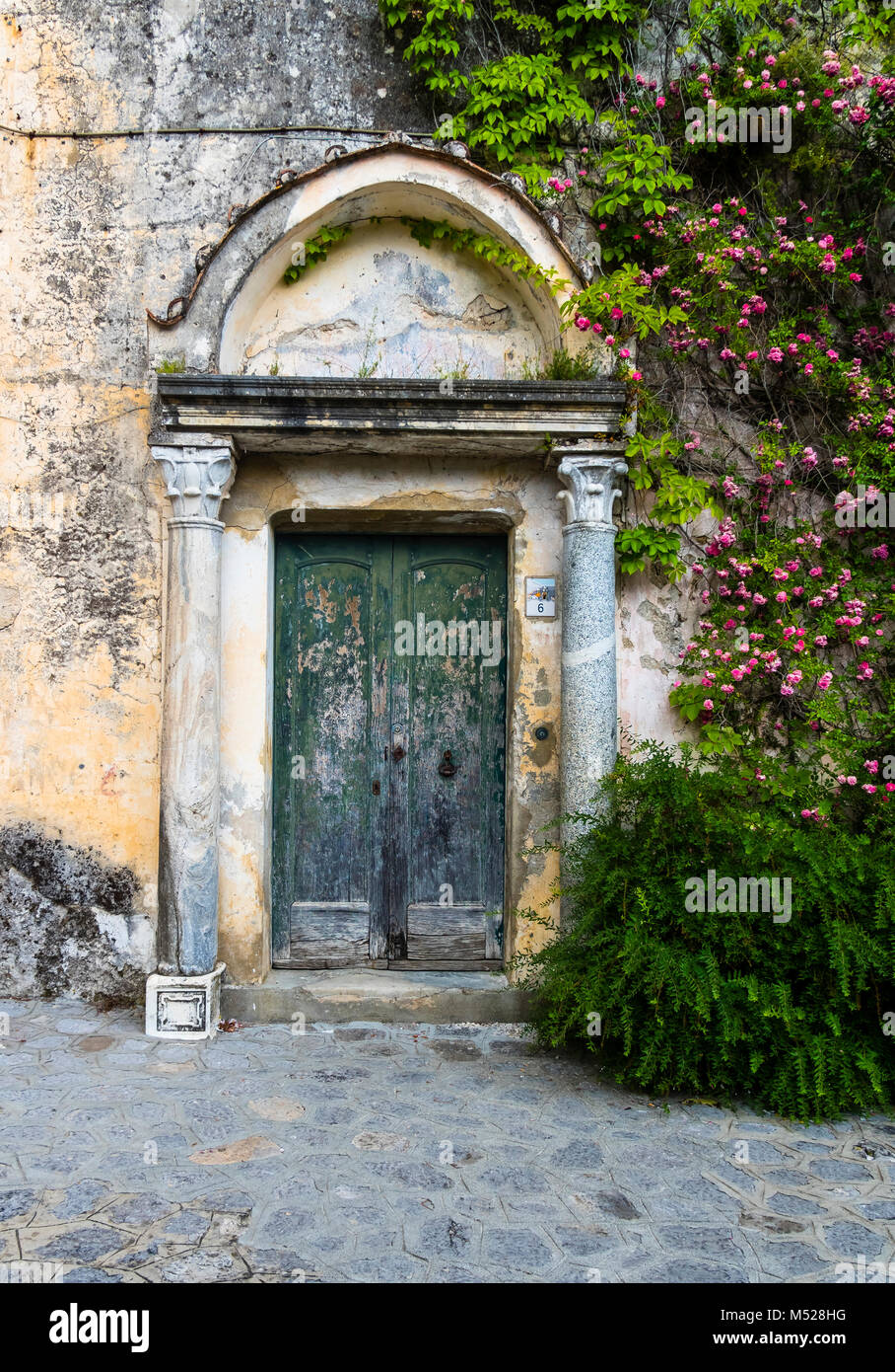 Weathered entrance door with climbing roses,Ravello,province of Salerno,Amalfi Coast,Campania,Italy Stock Photo