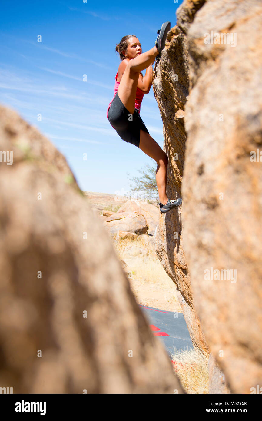 Side view of young woman climbing boulder, Brandberg, Damaraland