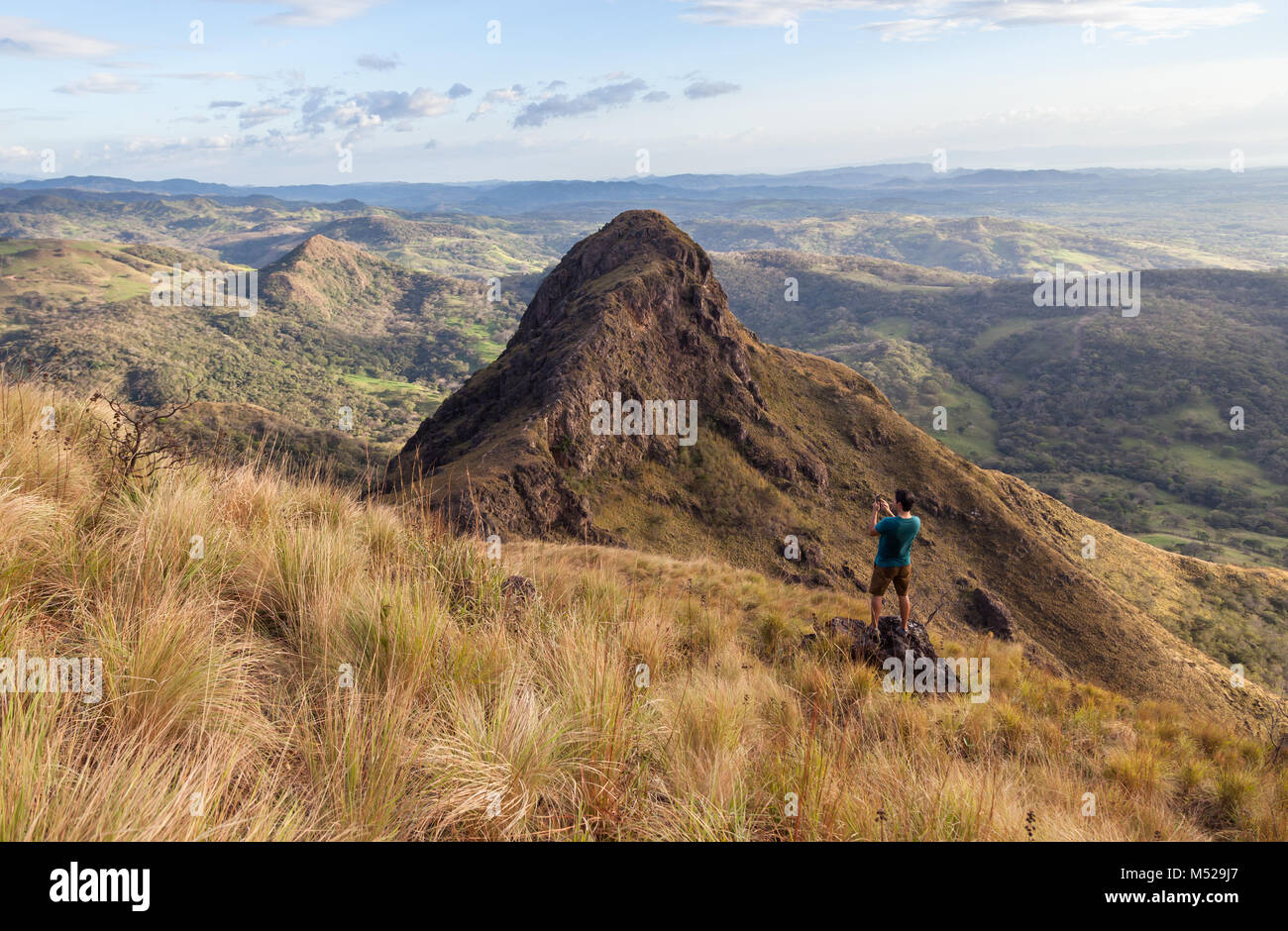 Man capturing the views of Guanacaste Costa Rica from the top of this local treasure, Cerro Pelado at sunset Stock Photo