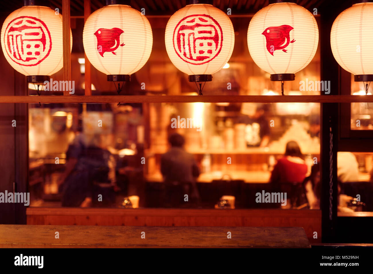 People dining inside a traditional Japanese restaurant with lanterns lit up at night. Gion, Kyoto, Japan 2017. Stock Photo