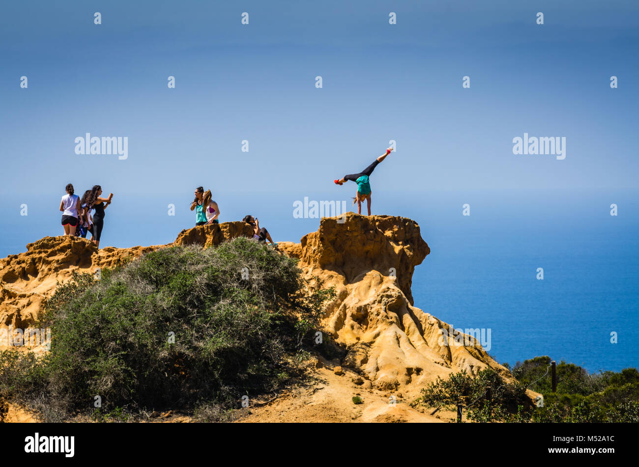 Woman strikes a handstand yoga pose for a photograph on a cliff at Torrey Pines State Natural Reserve, near San Diego, California. Stock Photo