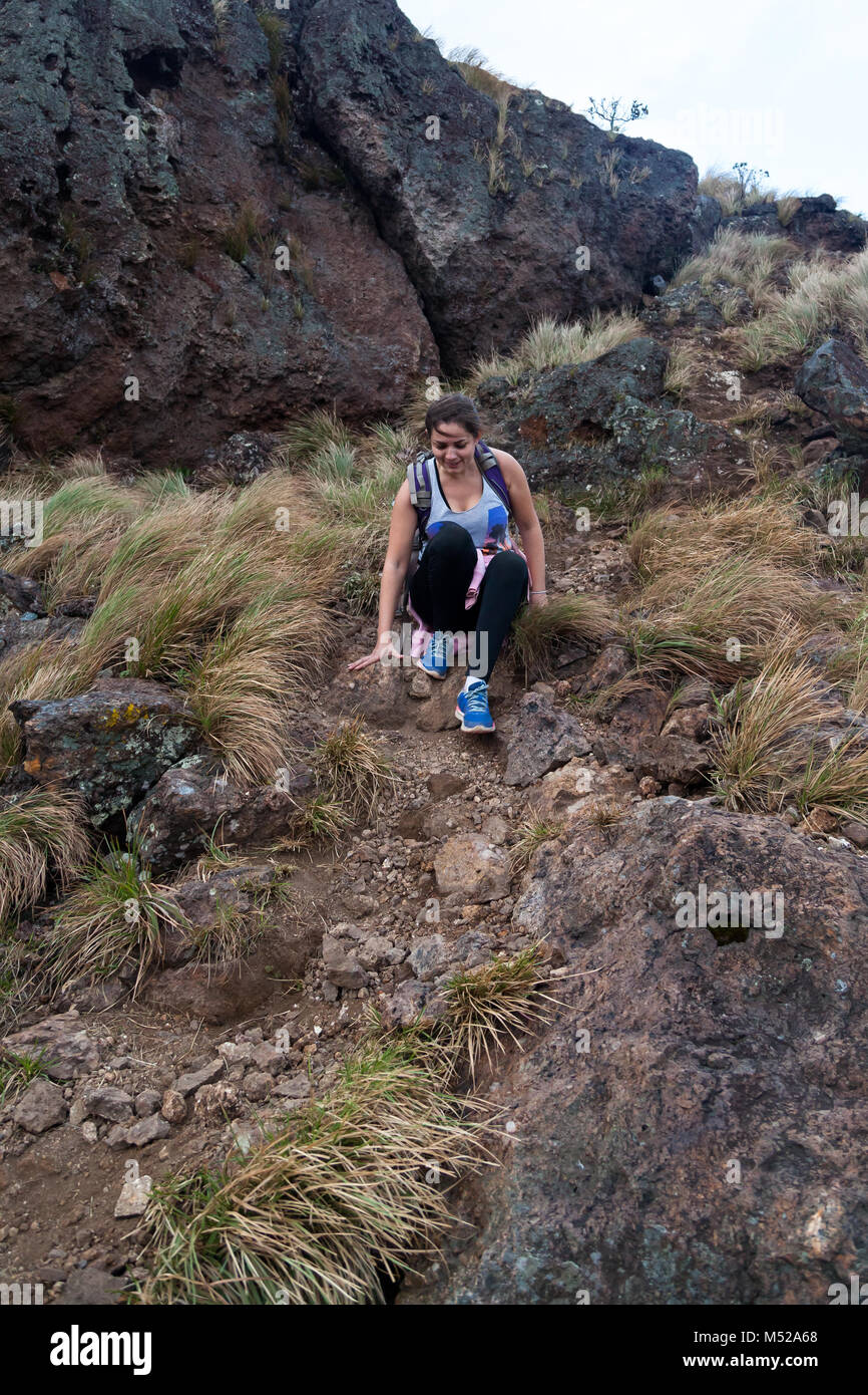 young woman sliding down a rocky section of Cerro Pelado in Costa Rica Stock Photo