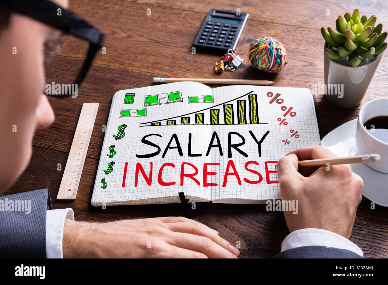 Businessman Drawing Salary Increase In Notepad At Desk Stock Photo Alamy