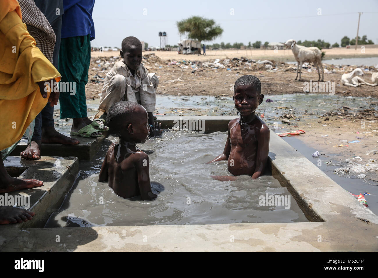 Children play in water in Muna Garage IDP camp. More than two million were displaced during the conflict with Boko Haram. Stock Photo
