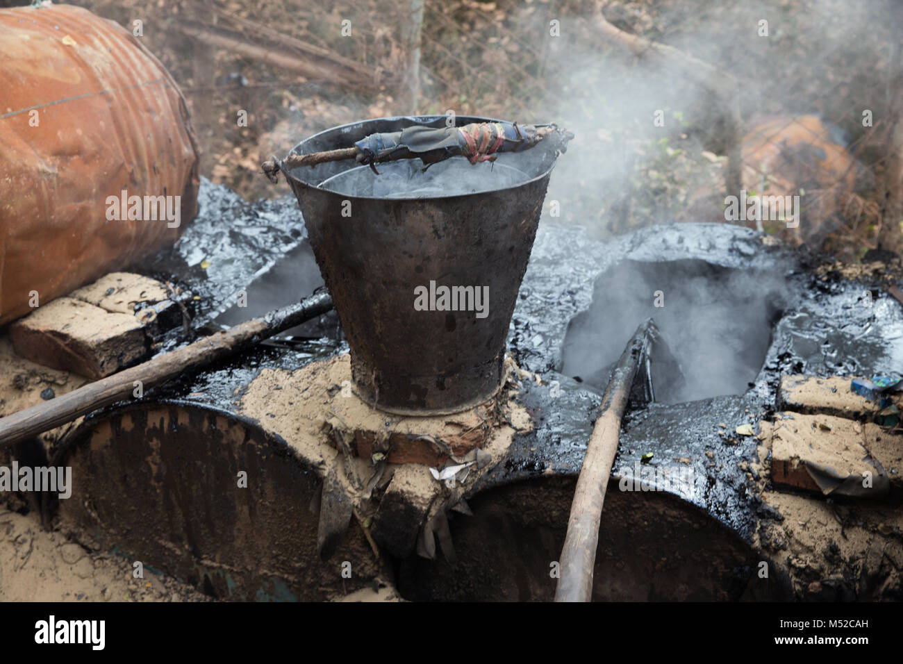 A bucket of tar hand made by Bengali men next to scorching fires in