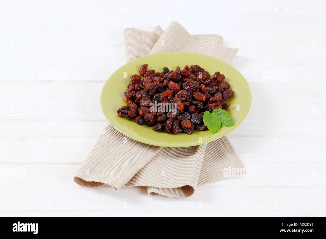 plate of sweet raisins on beige place mat Stock Photo