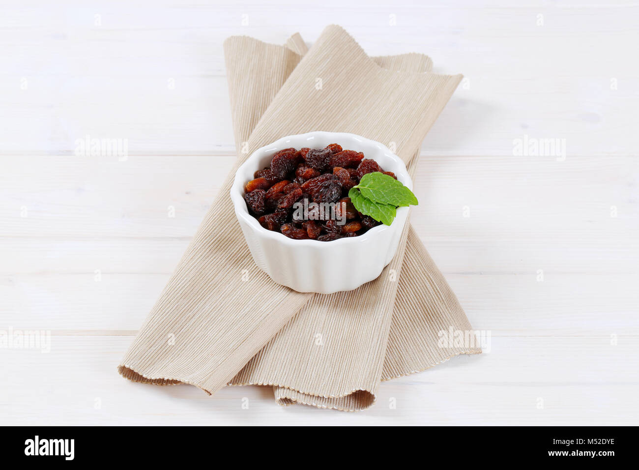 bowl of sweet raisins on beige place mat Stock Photo