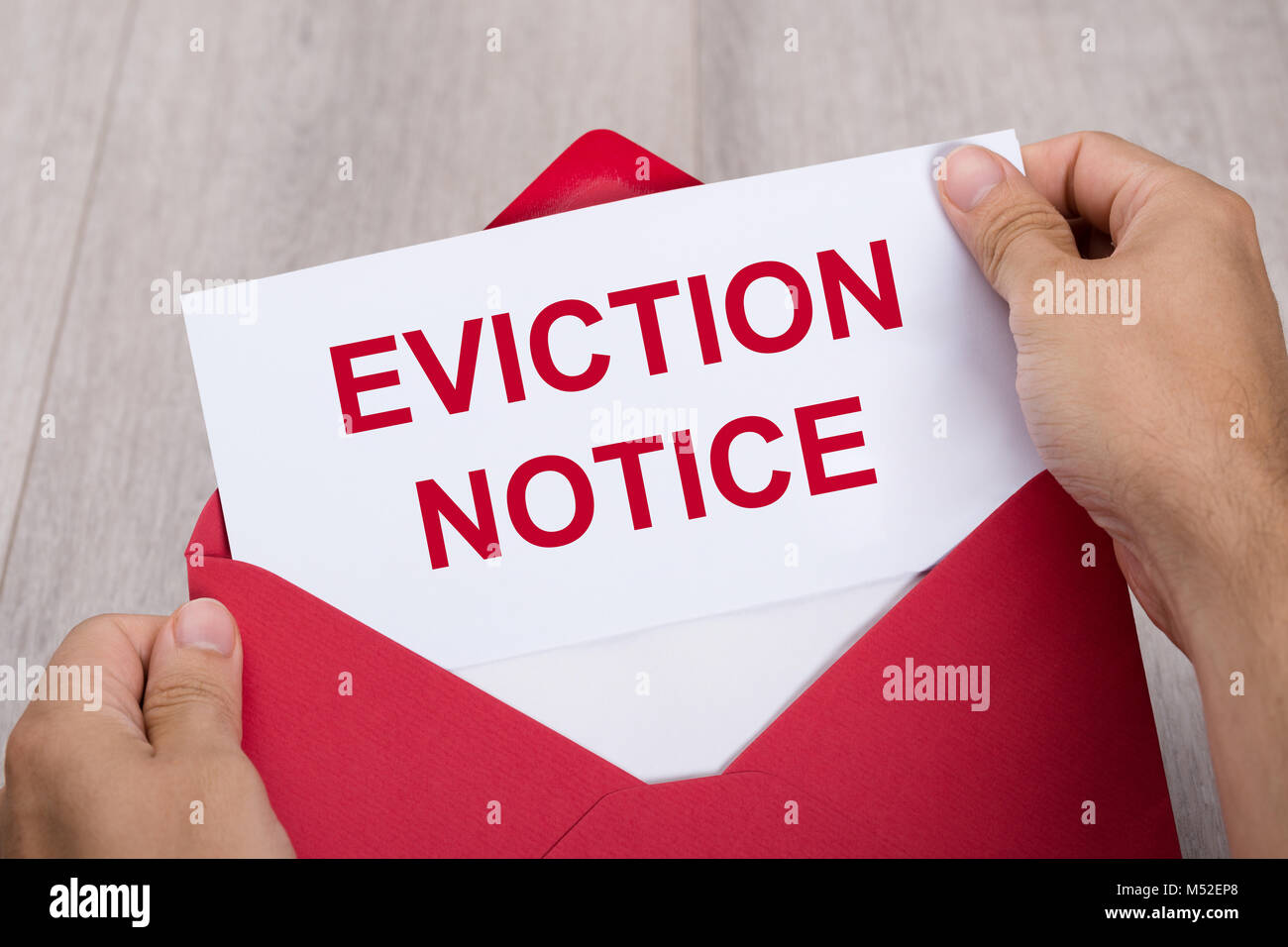 Close-up Of A Person's Hand Holding Eviction Notice In Red Envelope Stock Photo