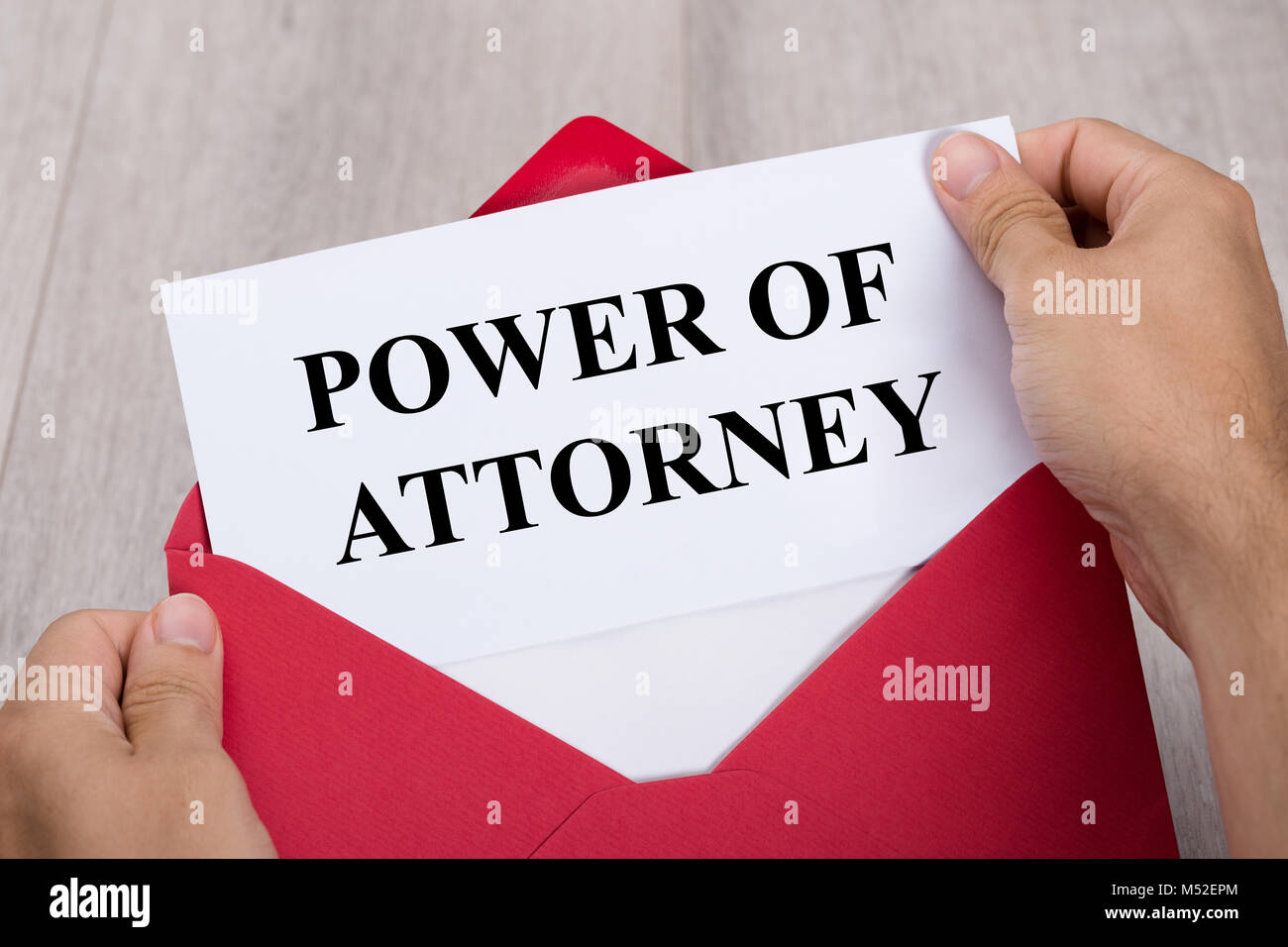 Close-up Of A Person's Hand Holding Power Of Attorney Document In Red Envelope Stock Photo