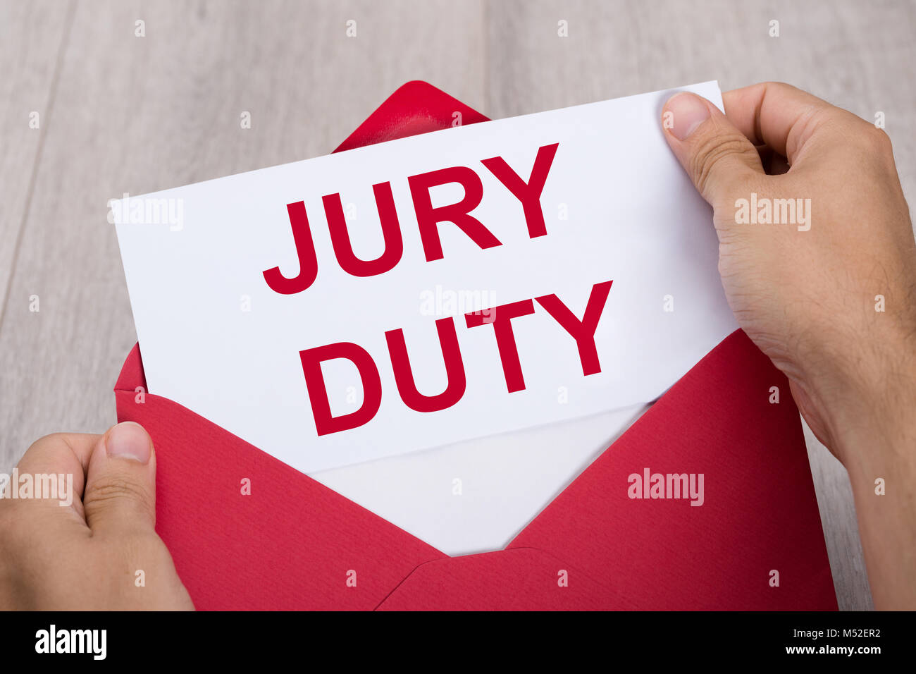Close-up Of A Human Hand Holding Jury Duty Document In Red Envelope Stock Photo