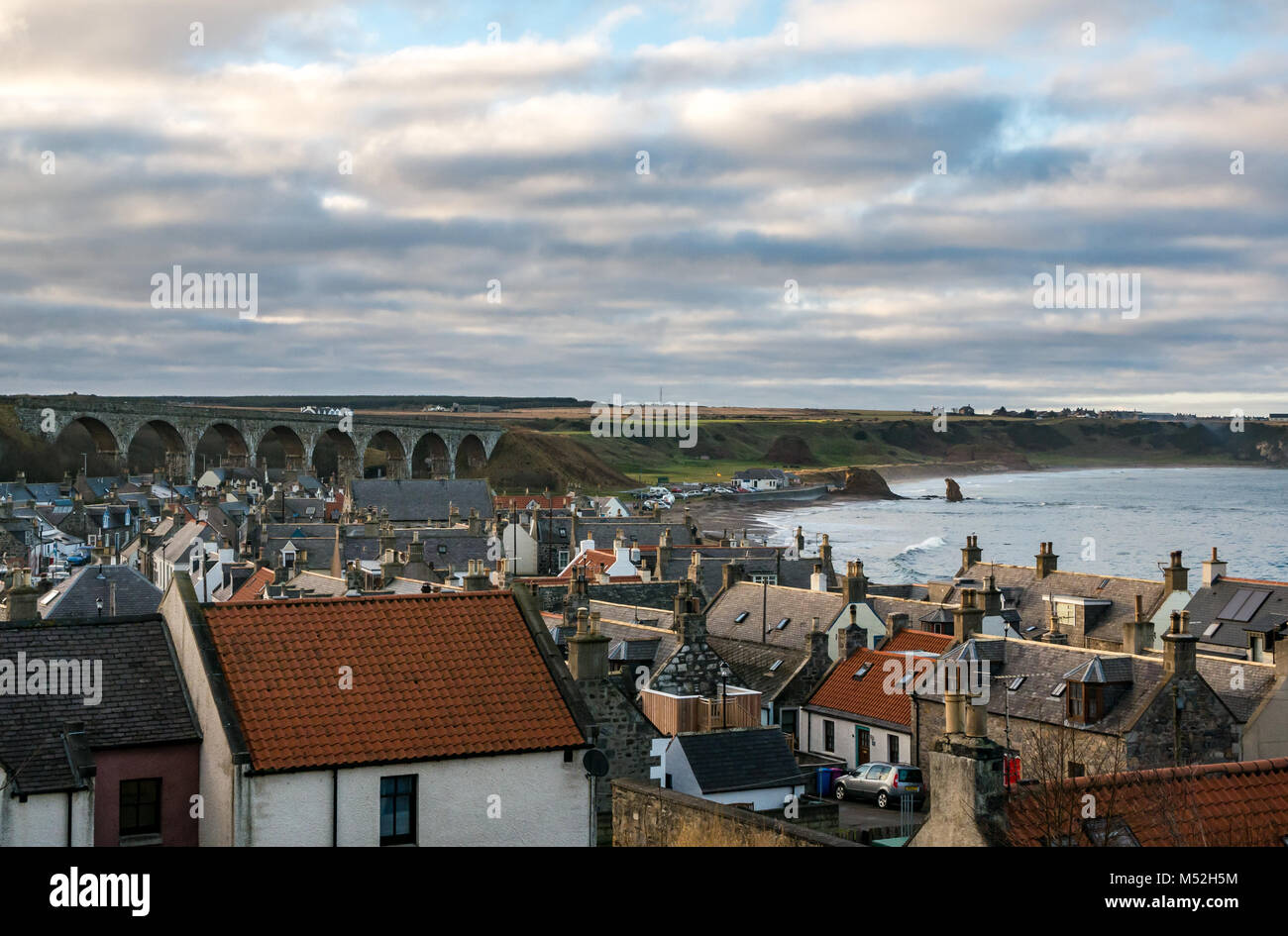 View of picturesque seaside town cottages, Victorian railway viaduct and sea stacks on beach in bay, Cullen, Moray, Scotland, UK Stock Photo