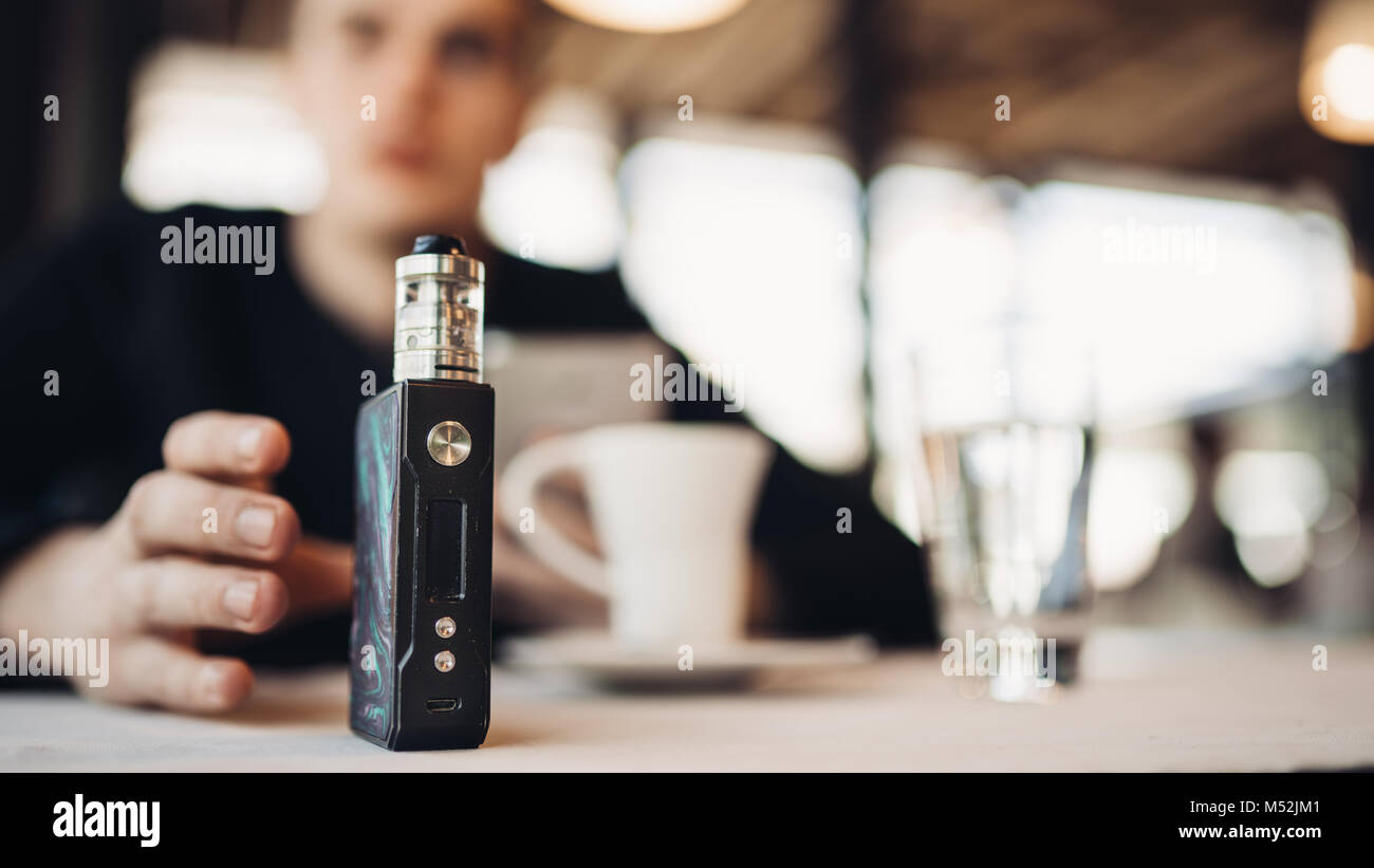 Using electronic cigarette to smoke in public places.Smoke restriction,smoking ban.Using vaping device with flavoured liquid.E-juice vaping new techno Stock Photo