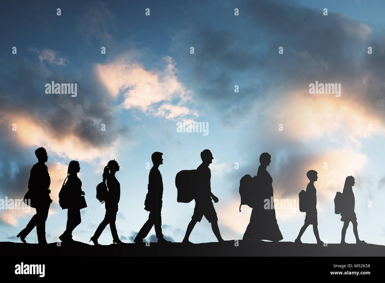 Silhouette Of Refugees People With Luggage Walking In A Row Stock Photo