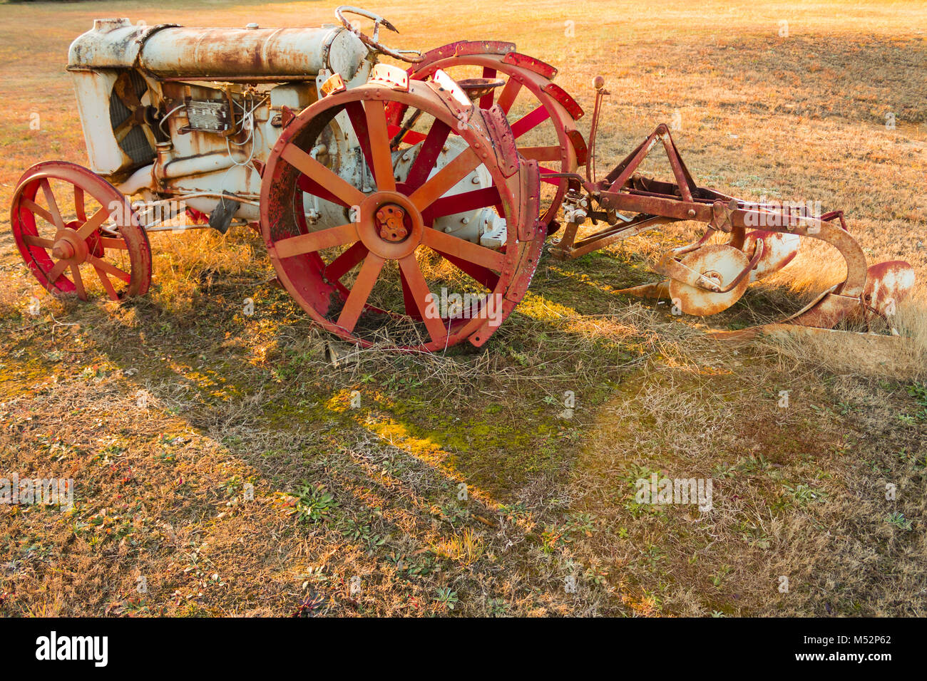 An old antique tractor and plow from the golden days of farming Stock Photo