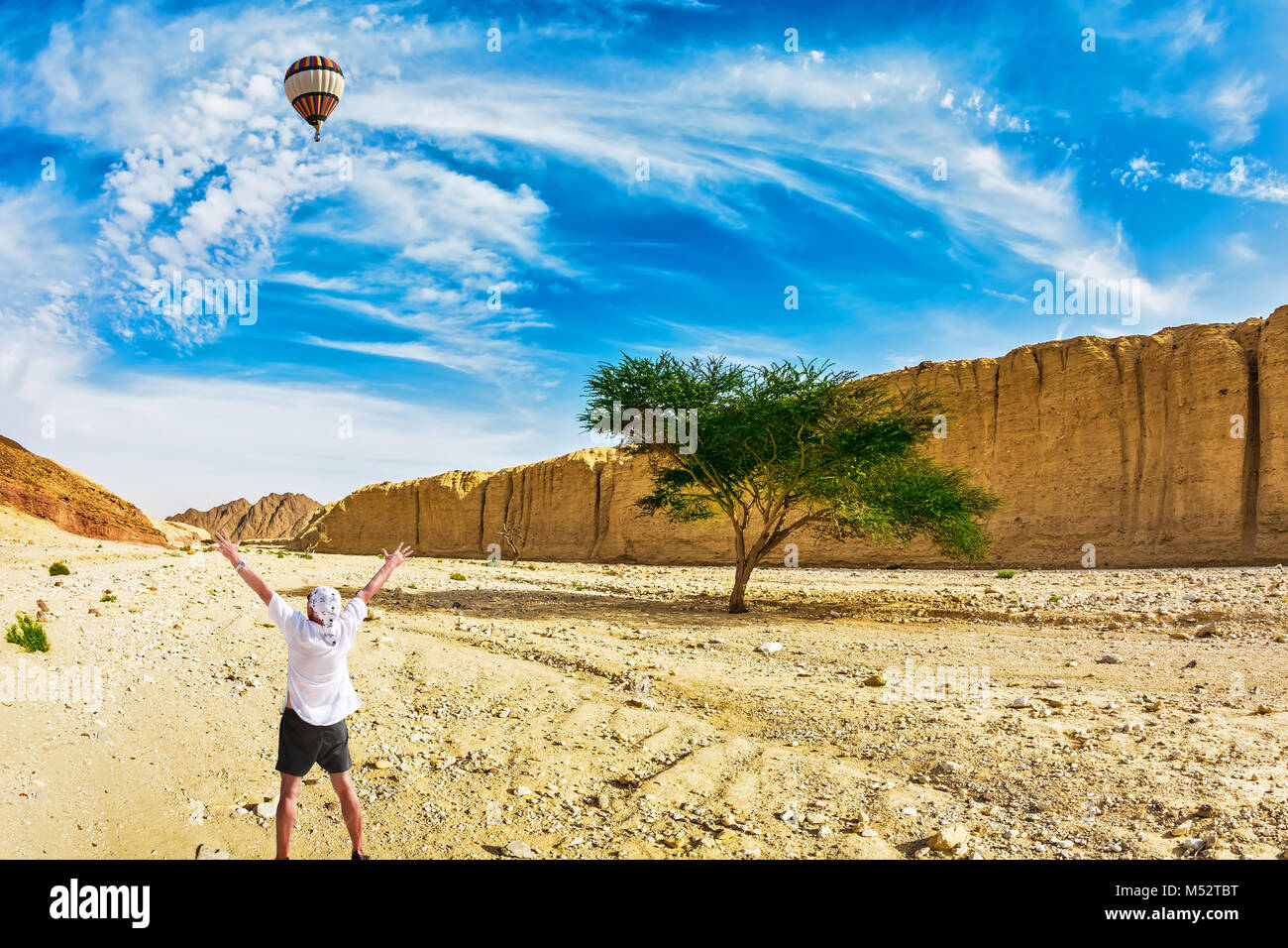 The huge multi-colored balloon flies over the hot desert Stock Photo